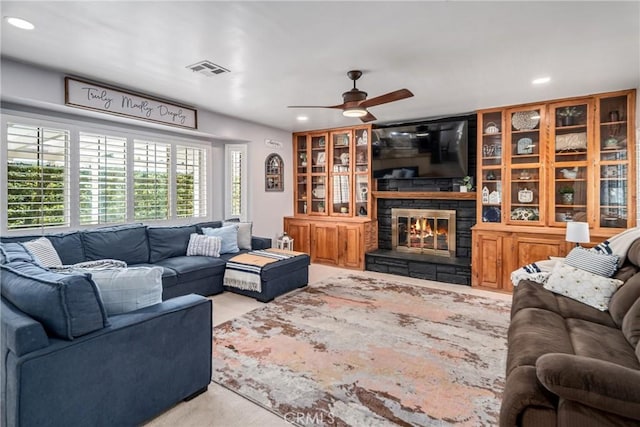 living room with ceiling fan and a stone fireplace