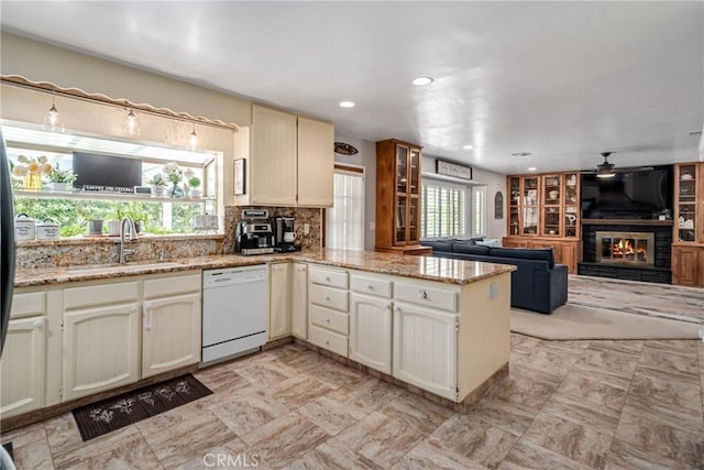 kitchen featuring dishwasher, kitchen peninsula, sink, light stone counters, and cream cabinets