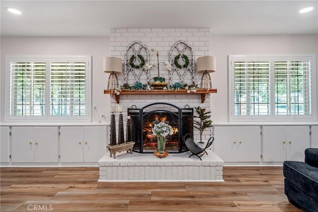living room with a brick fireplace, recessed lighting, and light wood-style flooring