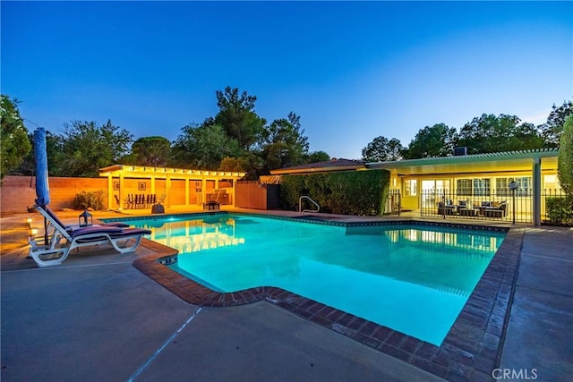 pool at dusk with a patio area