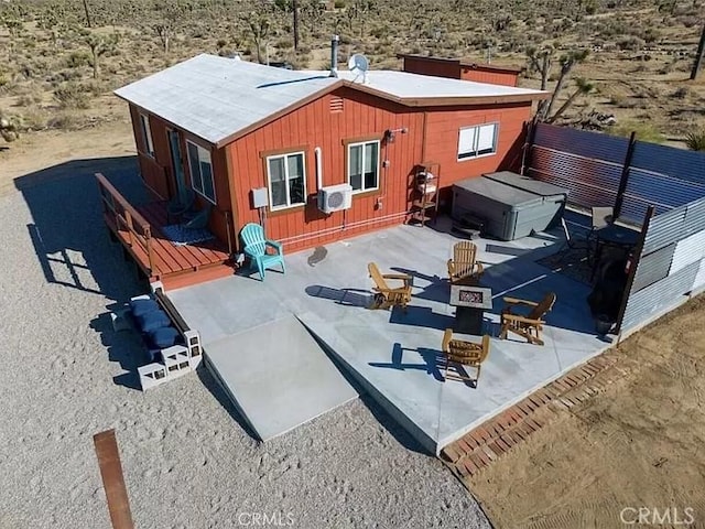 rear view of property featuring a wooden deck and a hot tub