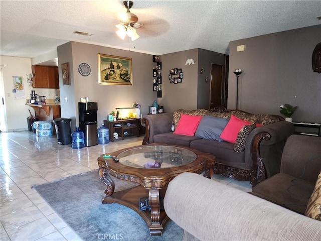 living room featuring ceiling fan, a textured ceiling, and light tile patterned floors