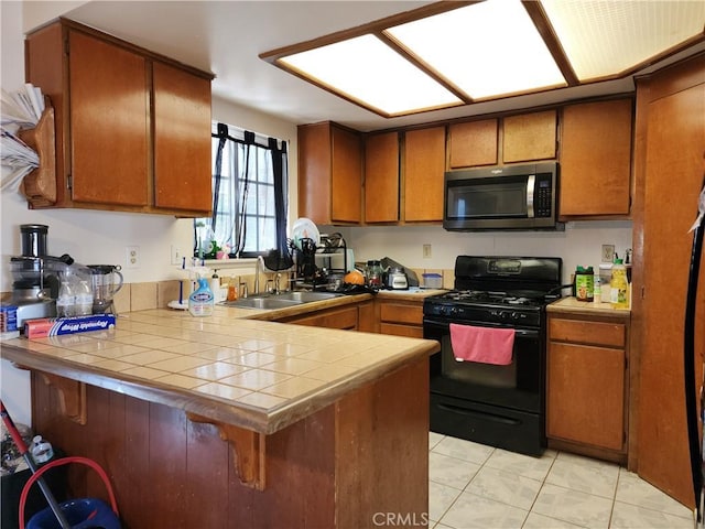 kitchen featuring light tile patterned flooring, sink, tile counters, kitchen peninsula, and gas stove