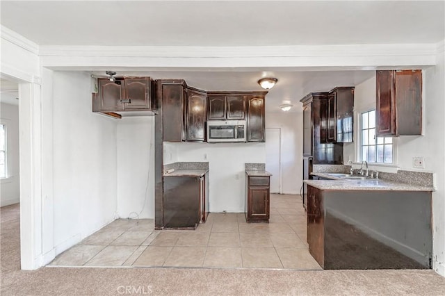 kitchen featuring sink, light colored carpet, and dark brown cabinetry