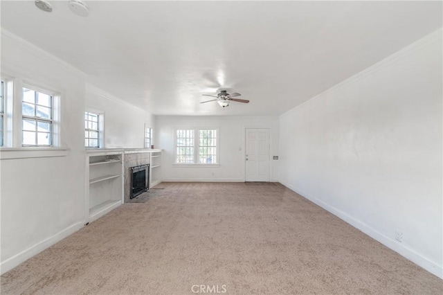 unfurnished living room featuring a tiled fireplace, ceiling fan, a wealth of natural light, and light carpet