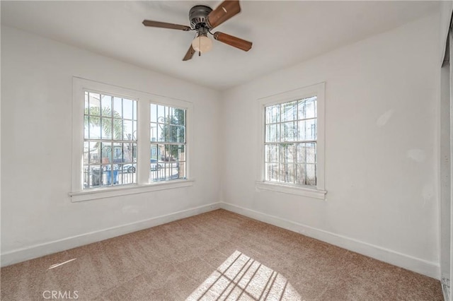 carpeted empty room featuring ceiling fan and a wealth of natural light