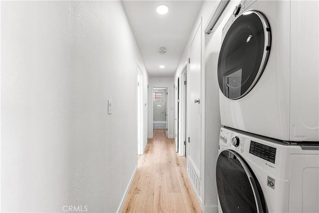 washroom featuring stacked washing maching and dryer and light hardwood / wood-style floors