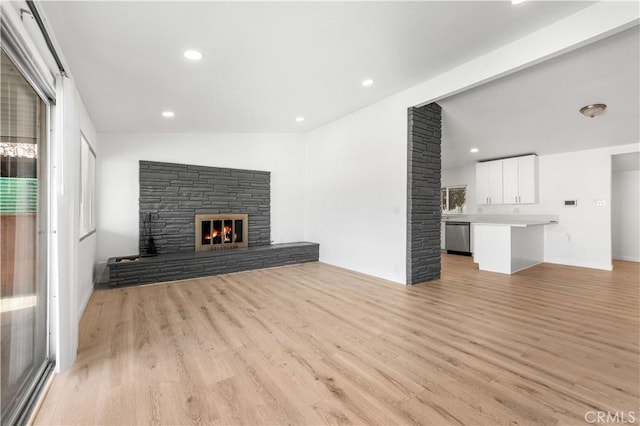 unfurnished living room with light wood-type flooring, vaulted ceiling, and a fireplace