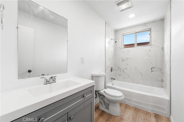 full bathroom featuring hardwood / wood-style flooring, tiled shower / bath combo, vanity, and toilet