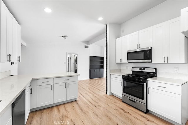 kitchen with white cabinets, stainless steel appliances, kitchen peninsula, light wood-type flooring, and light stone counters