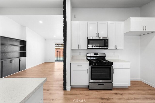 kitchen with light wood-type flooring, stainless steel appliances, and white cabinetry