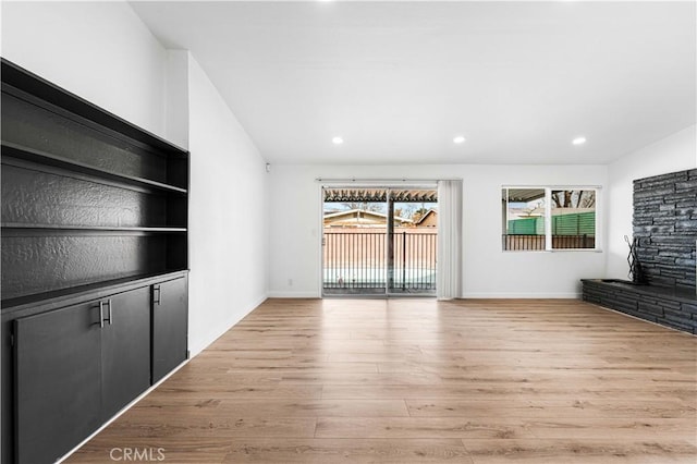 unfurnished living room with a healthy amount of sunlight, a fireplace, and light hardwood / wood-style flooring