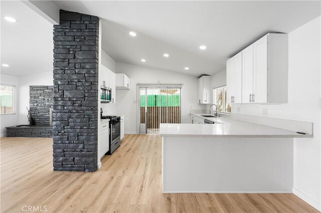 kitchen with white cabinetry, light hardwood / wood-style floors, kitchen peninsula, stainless steel appliances, and lofted ceiling