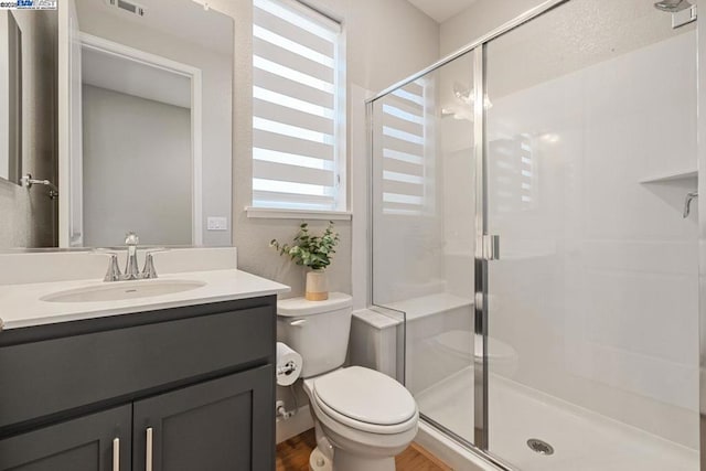 bathroom featuring toilet, vanity, a shower with shower door, and hardwood / wood-style flooring