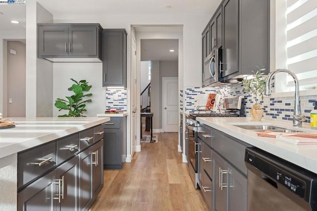 kitchen featuring decorative backsplash, sink, appliances with stainless steel finishes, and light hardwood / wood-style flooring