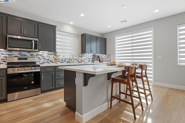 kitchen with light wood-type flooring, stainless steel appliances, and a center island