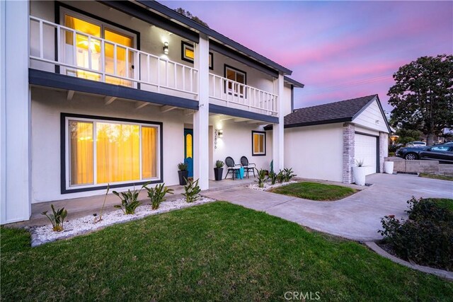 exterior space featuring a yard, a garage, and a balcony