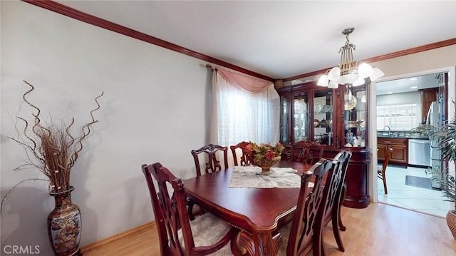 dining area with an inviting chandelier, ornamental molding, light hardwood / wood-style flooring, and sink