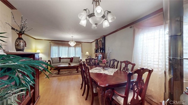 dining area with wood-type flooring, crown molding, and a chandelier