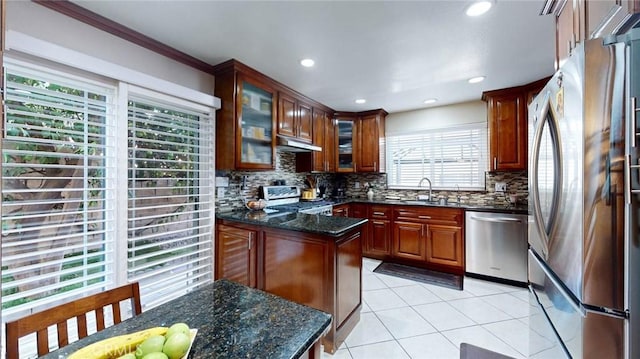 kitchen with light tile patterned floors, appliances with stainless steel finishes, tasteful backsplash, dark stone counters, and sink