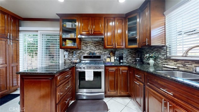 kitchen featuring dark stone counters, decorative backsplash, sink, light tile patterned floors, and stainless steel range with gas stovetop