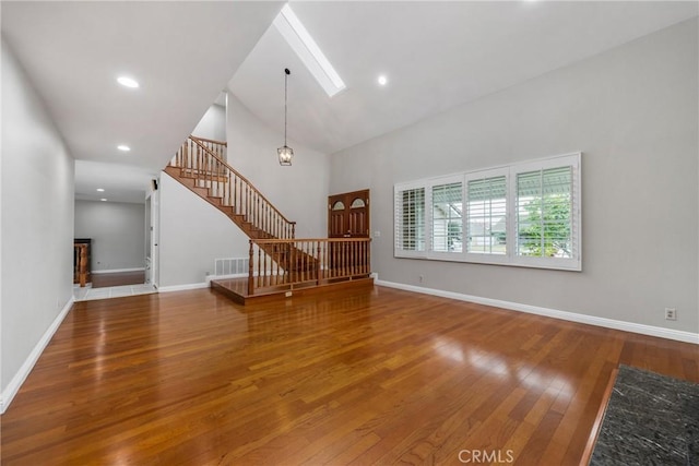 unfurnished living room featuring high vaulted ceiling and hardwood / wood-style flooring