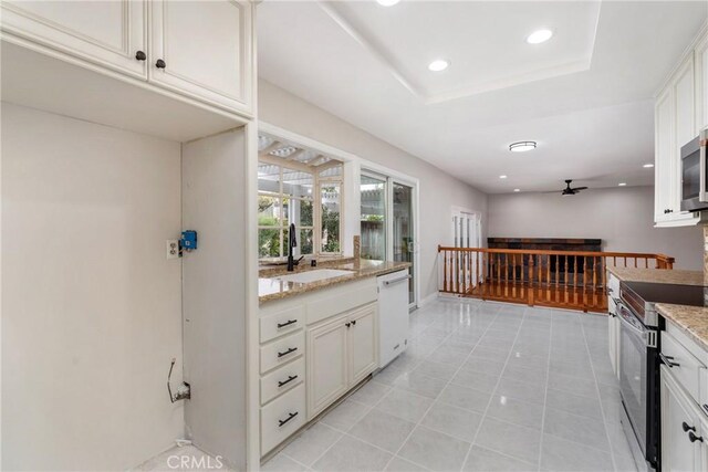 kitchen with light stone countertops, stainless steel appliances, white cabinets, and sink