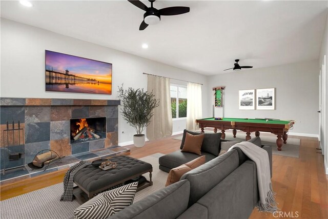 living room featuring ceiling fan, a tiled fireplace, light hardwood / wood-style flooring, and billiards