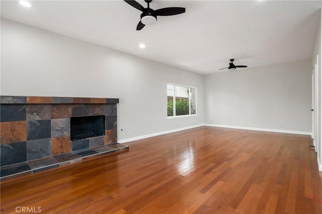 unfurnished living room featuring a fireplace, recessed lighting, ceiling fan, wood finished floors, and baseboards