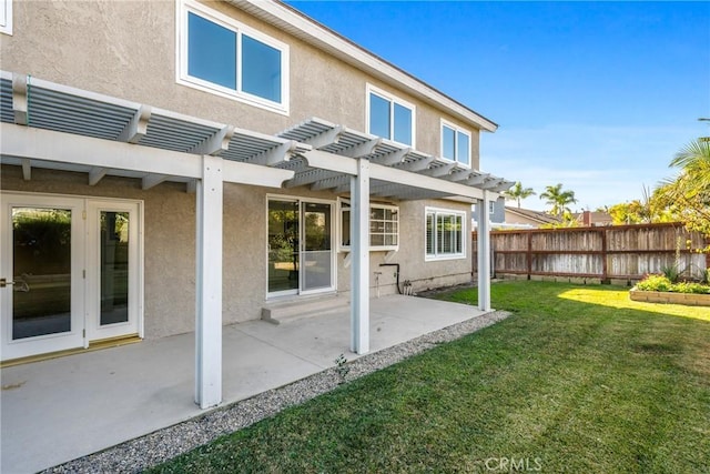 rear view of property with a yard, a patio, stucco siding, fence, and a pergola