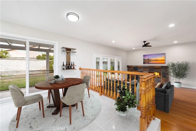 tiled dining area with ceiling fan, a healthy amount of sunlight, and a tile fireplace