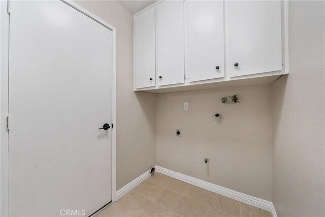 laundry area featuring gas dryer hookup, hookup for a washing machine, light tile patterned floors, electric dryer hookup, and cabinets