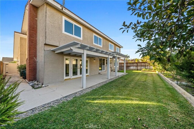 back of property with a pergola, a patio area, and a yard