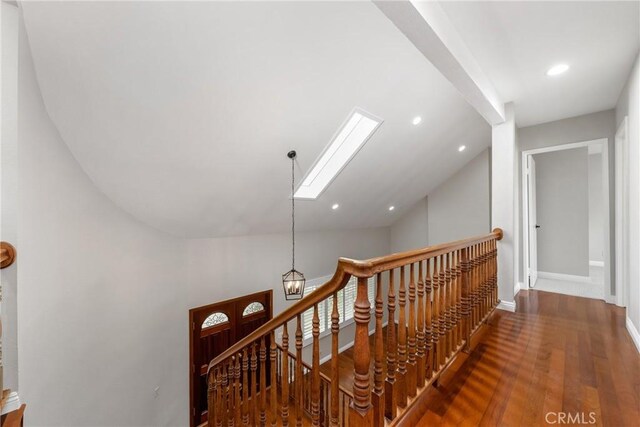 hallway with wood-type flooring, lofted ceiling, and an inviting chandelier