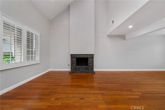 unfurnished living room with vaulted ceiling, a fireplace, and hardwood / wood-style flooring