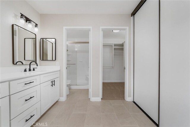 bathroom with toilet, walk in shower, vanity, and tile patterned flooring