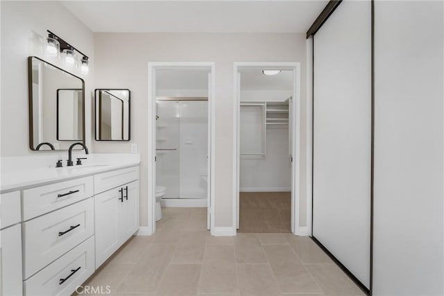 bathroom with a spacious closet, toilet, a shower stall, vanity, and tile patterned flooring