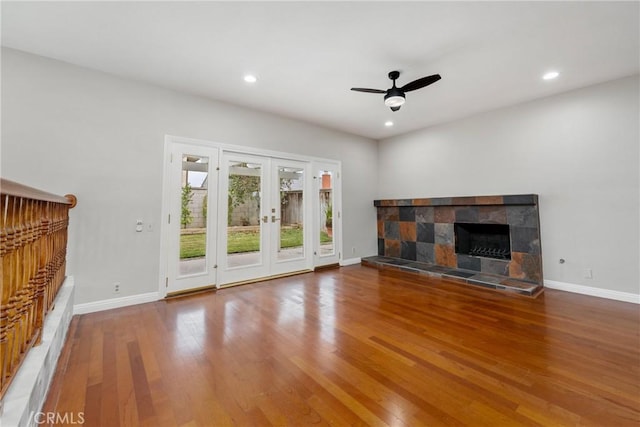 unfurnished living room with ceiling fan, wood-type flooring, french doors, and a fireplace