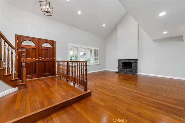 foyer entrance featuring stairs, high vaulted ceiling, wood finished floors, and baseboards