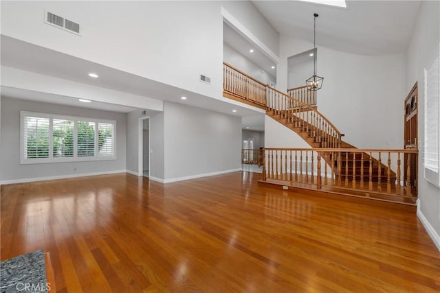 unfurnished living room featuring hardwood / wood-style floors and a high ceiling