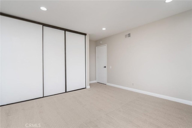 unfurnished bedroom featuring recessed lighting, light carpet, visible vents, baseboards, and a closet