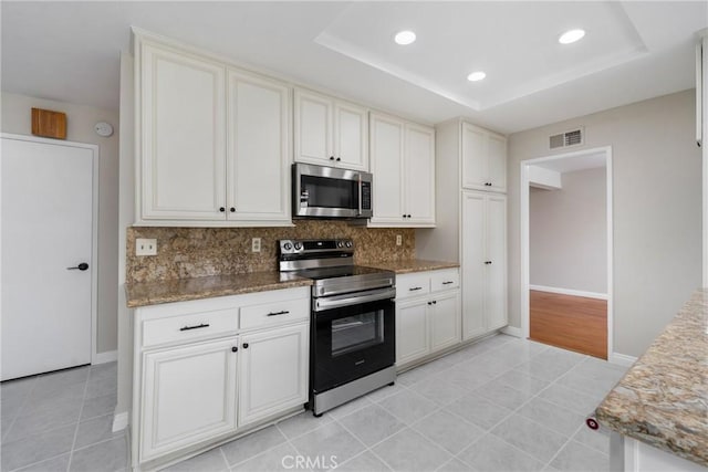 kitchen with light tile patterned floors, a tray ceiling, and stainless steel appliances