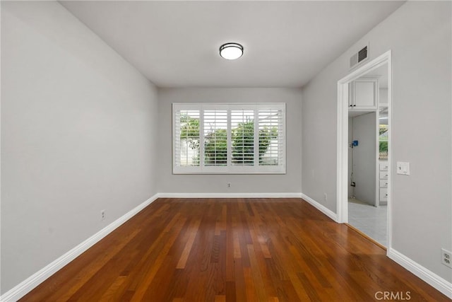 spare room featuring visible vents, baseboards, and wood finished floors