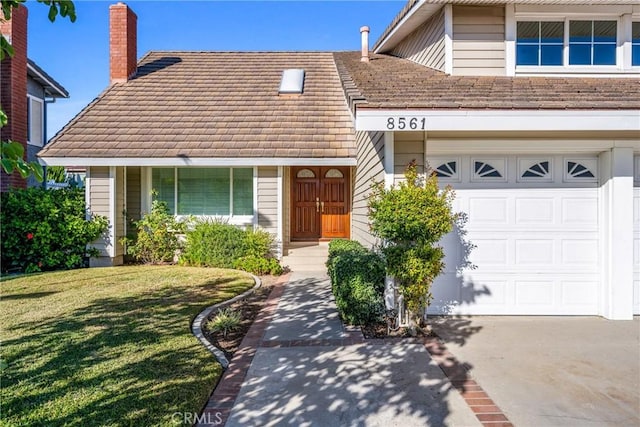 view of front of property featuring a garage, concrete driveway, a front lawn, and a chimney