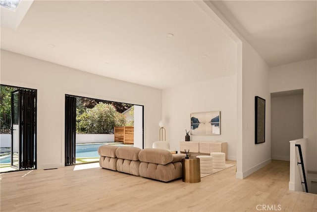 living room featuring light hardwood / wood-style flooring and a skylight