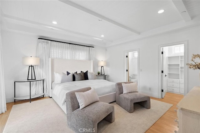 bedroom featuring hardwood / wood-style floors, ensuite bath, a closet, a walk in closet, and beamed ceiling