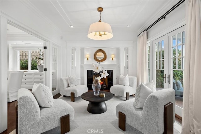 living area featuring crown molding, a healthy amount of sunlight, and french doors