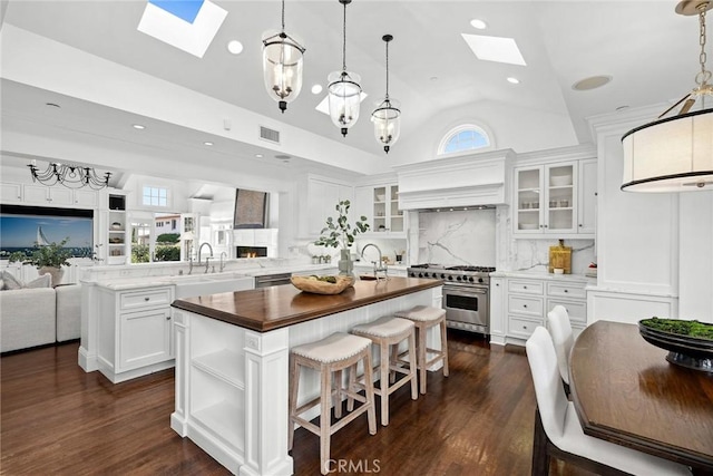 kitchen featuring white cabinets, appliances with stainless steel finishes, an island with sink, sink, and backsplash