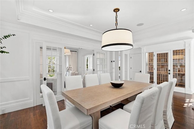 dining space featuring dark wood-type flooring, crown molding, and a tray ceiling