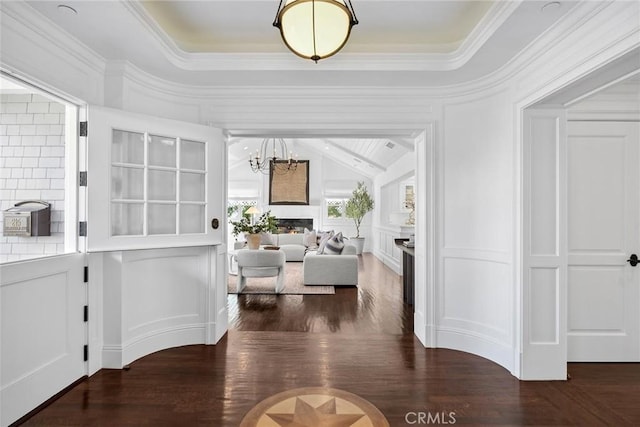 interior space with a tray ceiling, dark hardwood / wood-style flooring, crown molding, and an inviting chandelier